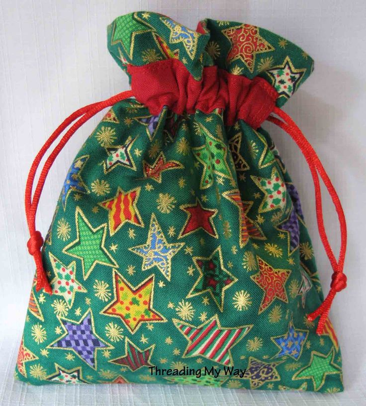 a small green bag with red string and stars on it, sitting on a white surface