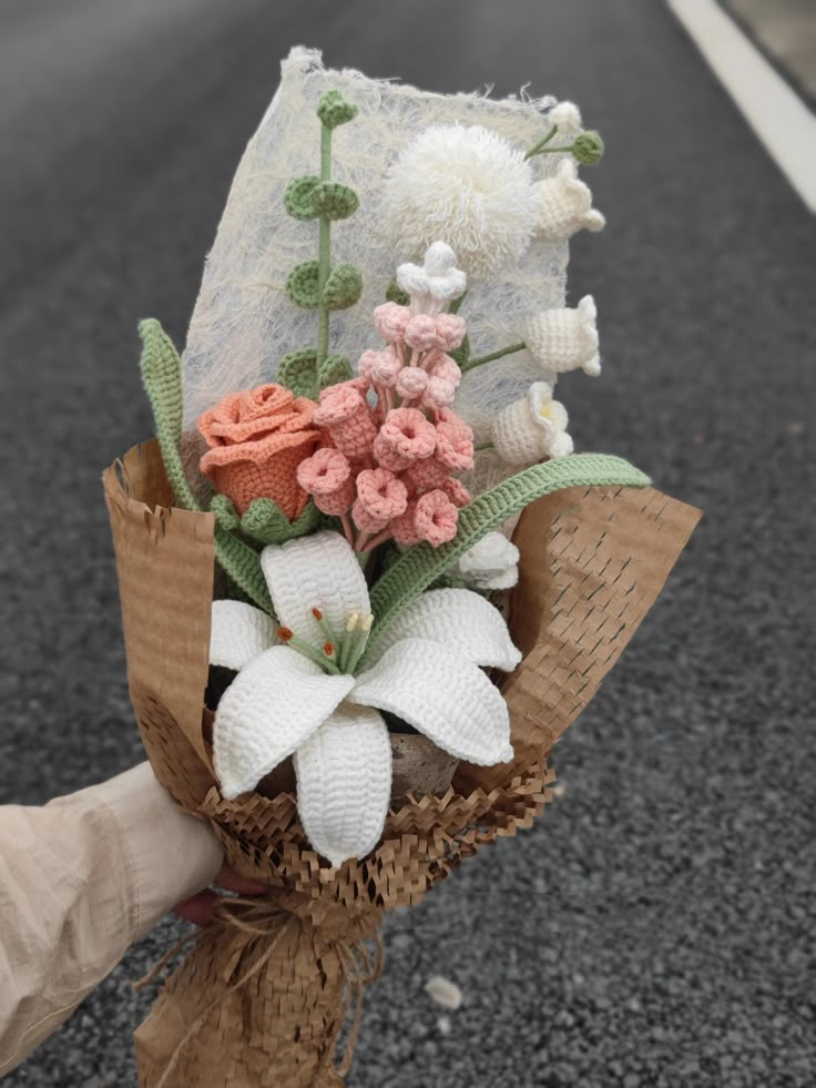 someone is holding a bouquet of flowers on the street