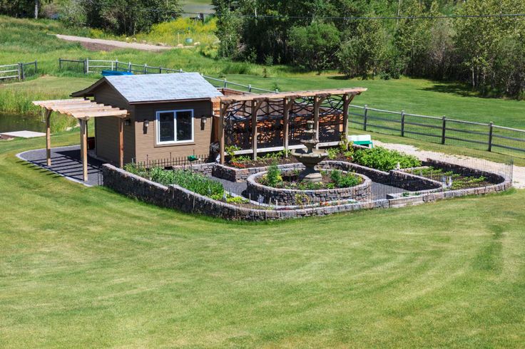 an aerial view of a small house in the middle of a grassy area with a pond