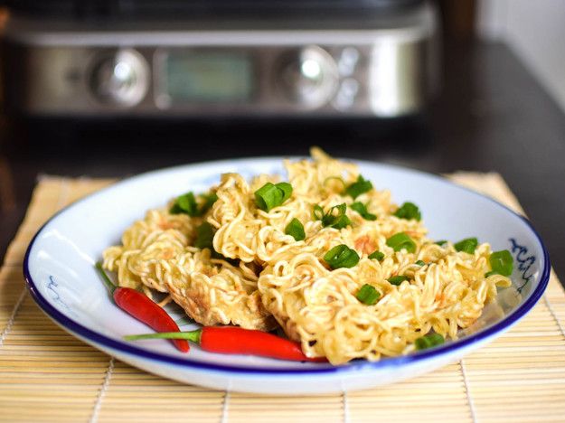 a white plate topped with noodles and veggies on top of a bamboo mat