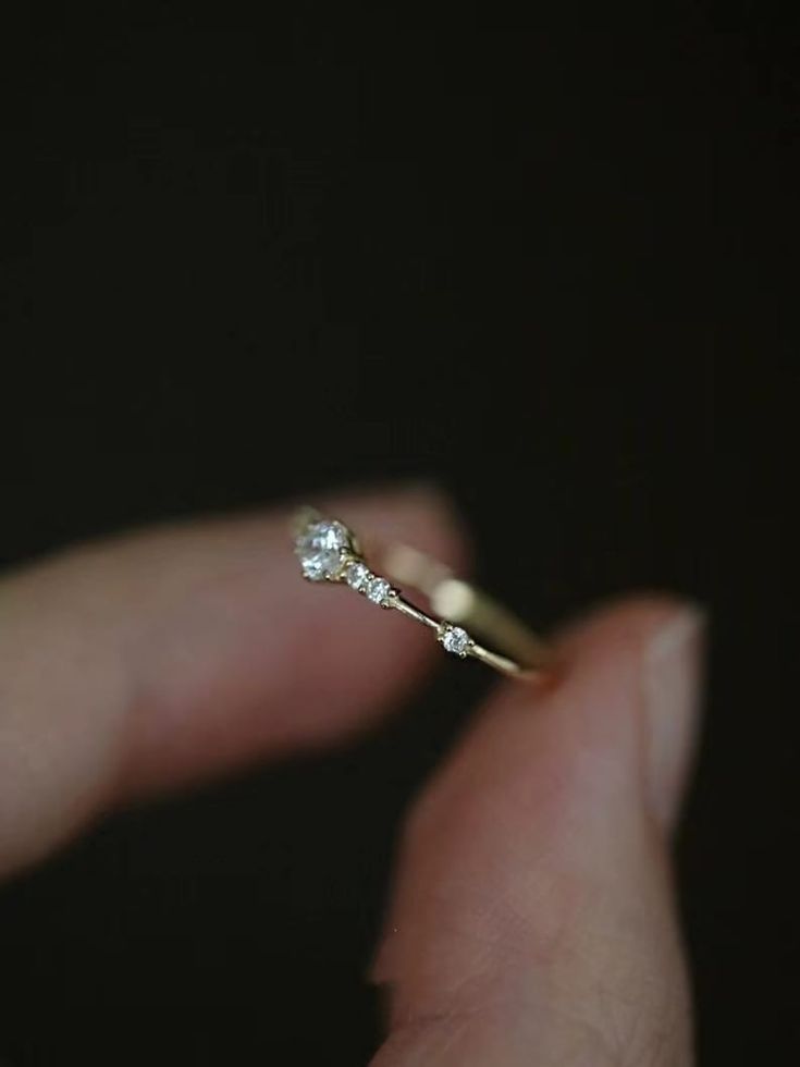 a person's hand holding a diamond ring