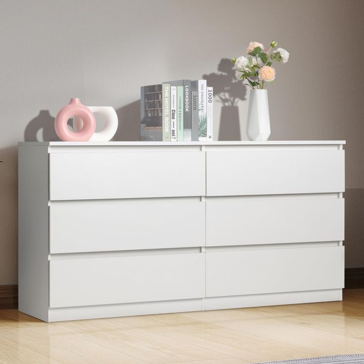 a white dresser with books and vases on top