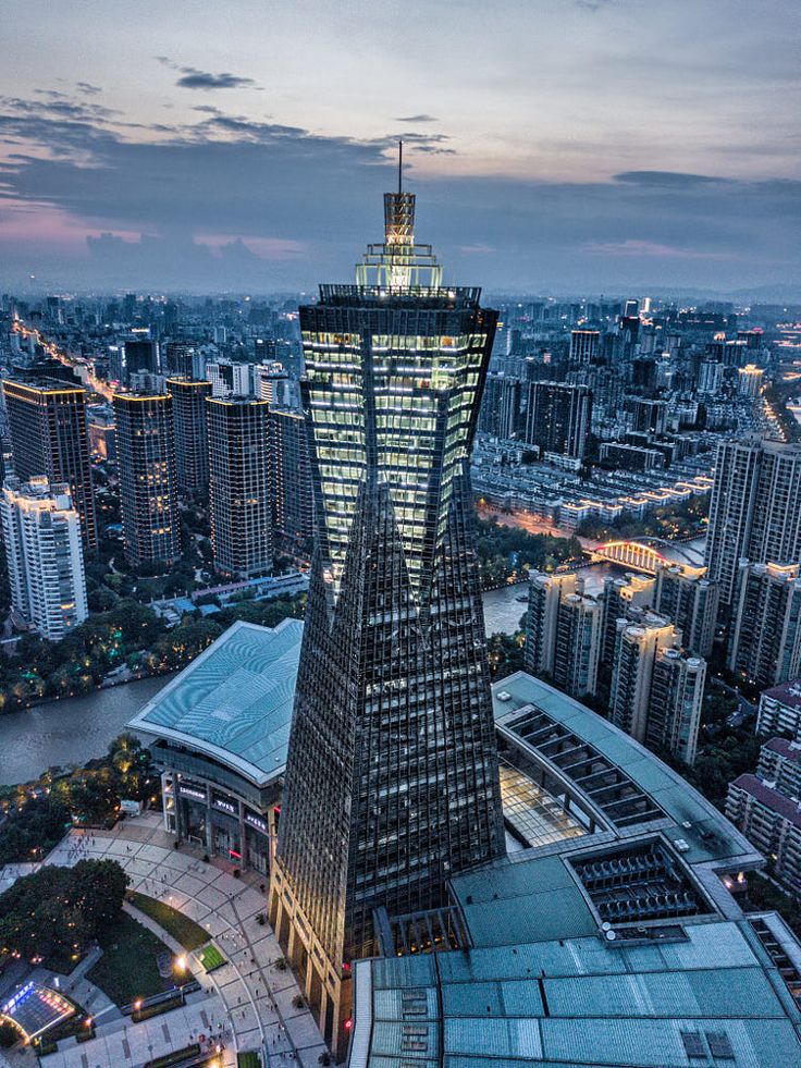 an aerial view of a very tall building in the middle of a city at night