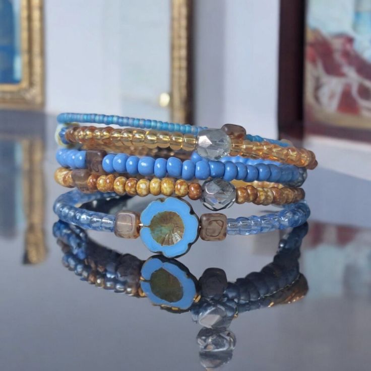 a stack of bracelets sitting on top of a table next to a framed painting