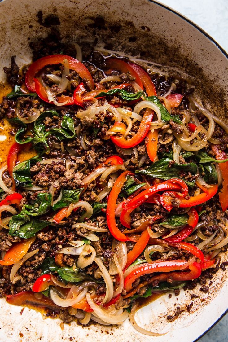 a skillet filled with noodles, meat and veggies on top of a table