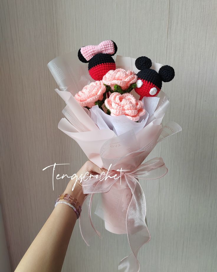 a person holding a bouquet of flowers with minnie mouse decorations on it's head