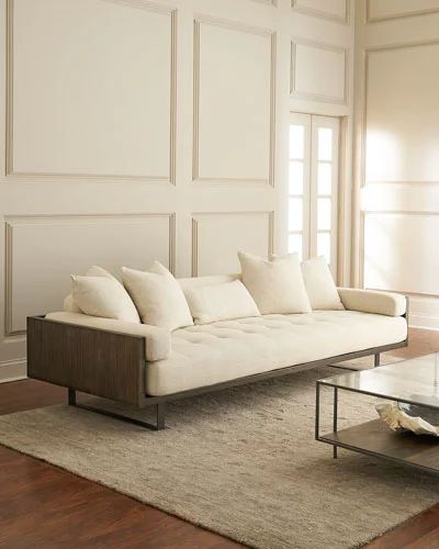 a white couch sitting on top of a wooden floor next to a glass coffee table