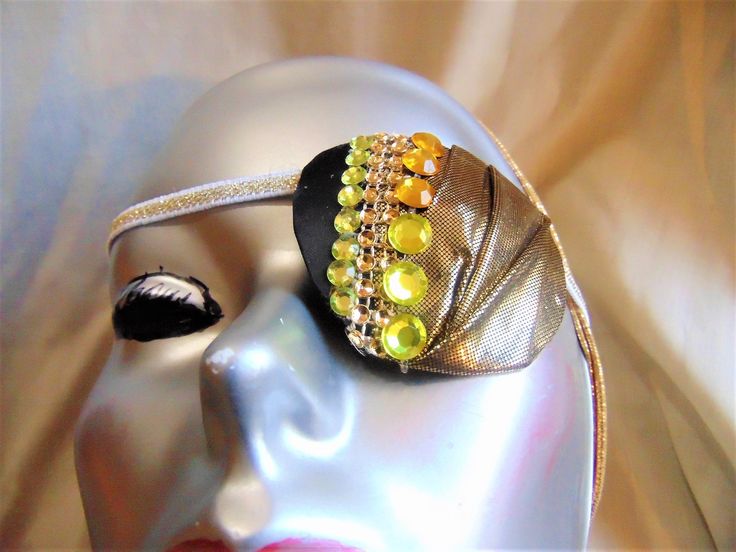 Women's eye patch, "ENTICEMENT" expertly handmade with metallic gold fabric creatively creased, mesh rhinestones and gemstones. The backing is soft recycled fabric for comfort. This is a ONE OF A KIND haute couture accessory. Wear it for a fashion statement or for an eye ailment such as cataracts. One size fits all and ideal for either eye. Handmade Adjustable Gold Headpiece, Bedazzled Gold Jewelry For Party, Adjustable Bedazzled Gold Jewelry, Gold Bedazzled Jewelry For Party, Adjustable Gold Headpieces For Evening, Party Gold Bedazzled Jewelry, Adjustable Headband For Masquerade, Adjustable Embellished Headpieces For Party, Handmade Gold Headpieces For Party