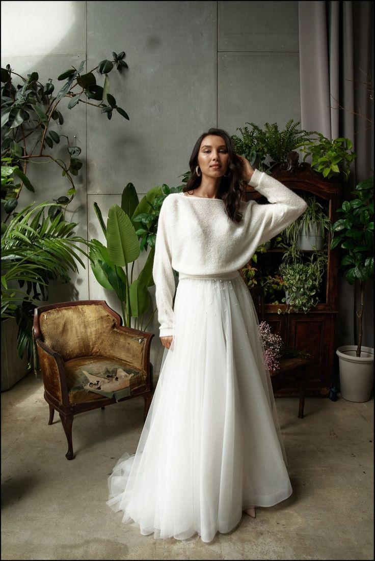 a woman in a white dress standing next to a chair