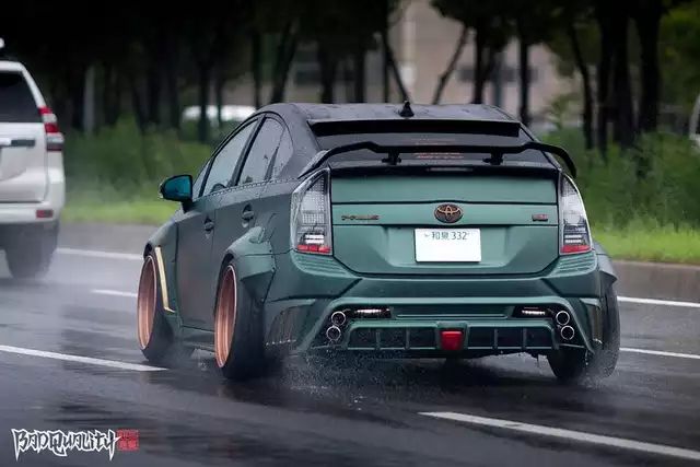 a green car driving down the road in the rain