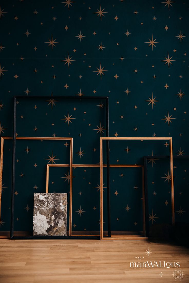 three frames against a blue wall with gold stars on the wall and in between them is a marble block