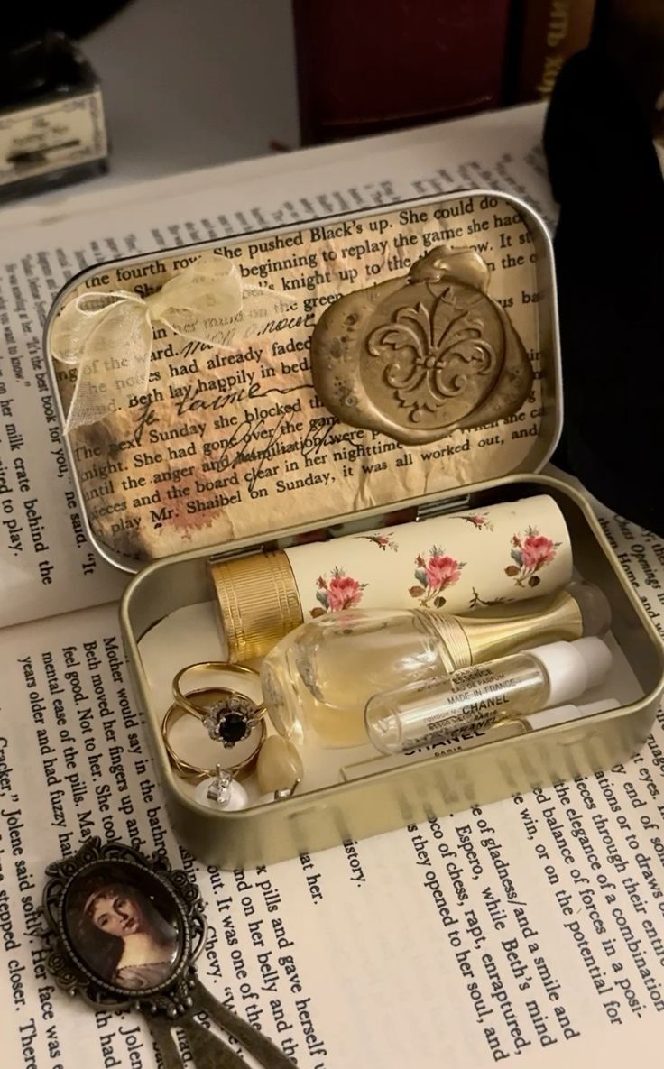 an open tin box with keys and other items in it on top of a book