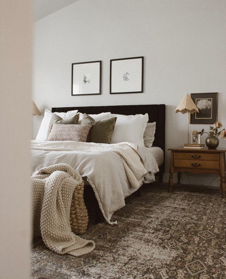 a bedroom with a bed, two pictures and a rug on the floor in front of it