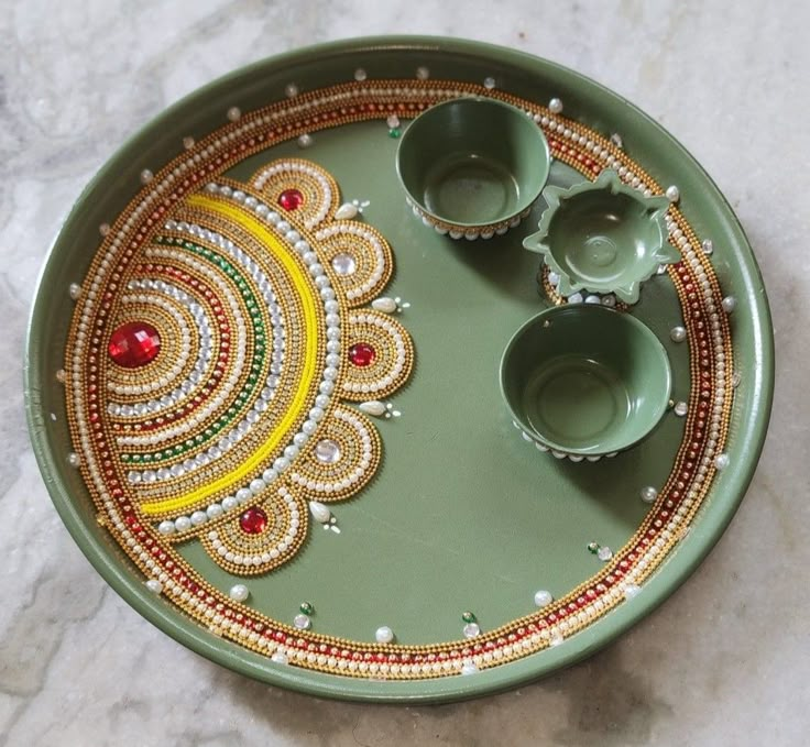 a green tray with three bowls and two cups on it sitting on a marble surface