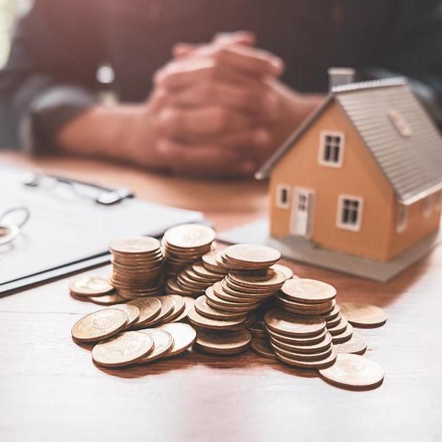 a pile of coins sitting on top of a wooden table next to a small house