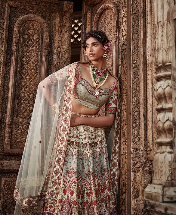 Editor's Note Featuring an elegant interplay of mughal and chintz motifs with intricate hand embroidery on the lehenga. It is paired with a meticulously embroidered blouse with intricate thread and hand beadwork on yoke and sleeves and styled with a co-ordinated dupatta. Fabric: Blouse: viscose silk, dupatta: net, lehenga skirt: viscose silk Color: Ivory Components: Lehenga, blouse and dupatta Occasion: Sangeet and Wedding Guest Care: Dry Clean Only About the Designer Kalista is a luxury fashion Cream Bollywood Lehenga With Floral Embroidery, Festive Cream Lehenga With Floral Embroidery, Elegant Multicolor Embroidery Sets For Reception, White Art Silk Lehenga With Intricate Embroidery, Elegant Art Silk Choli With Floral Embroidery, Silk Sets With Multicolor Embroidery For Wedding, Traditional Cream Choli With Floral Embroidery, Cream Embroidered Sets With Traditional Drape, Festive Cream Choli With Floral Embroidery