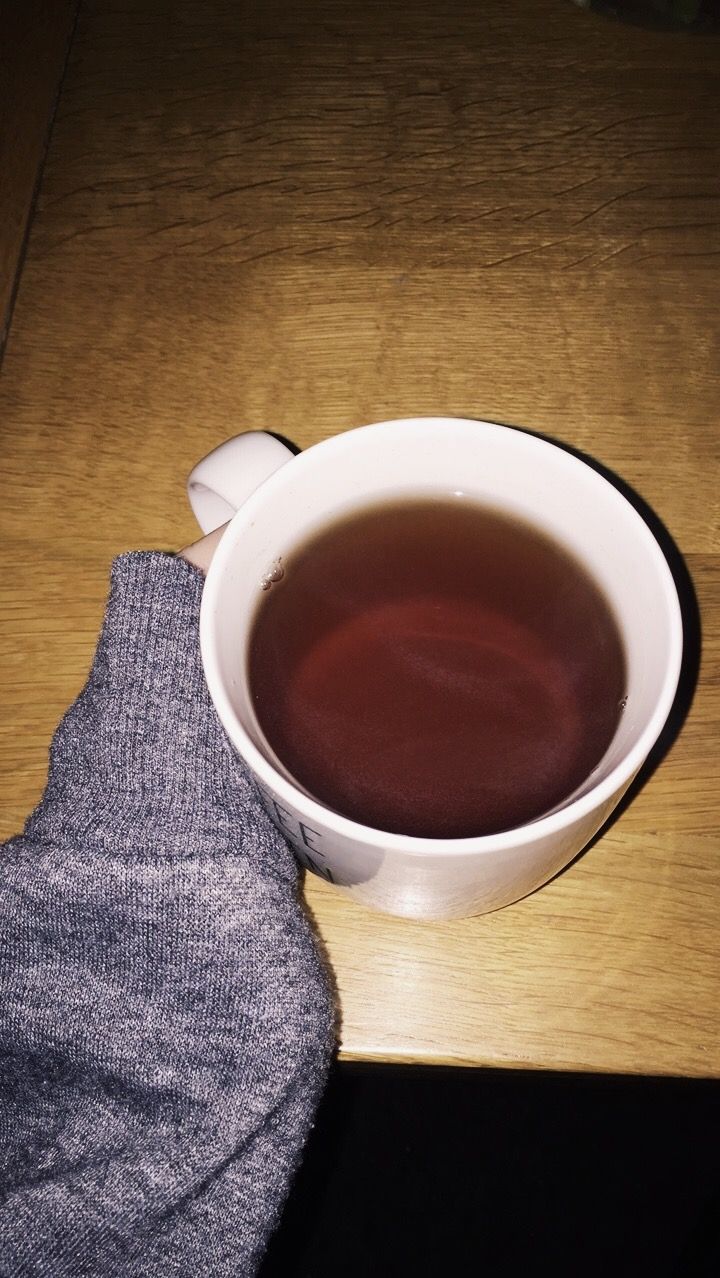 a cup of tea sitting on top of a wooden table next to a pair of gray socks