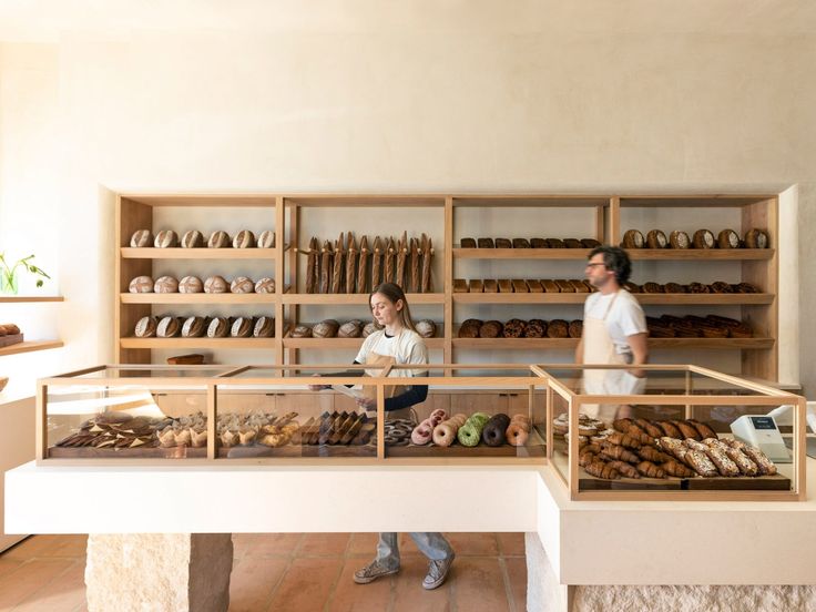 two people standing in front of a bakery counter