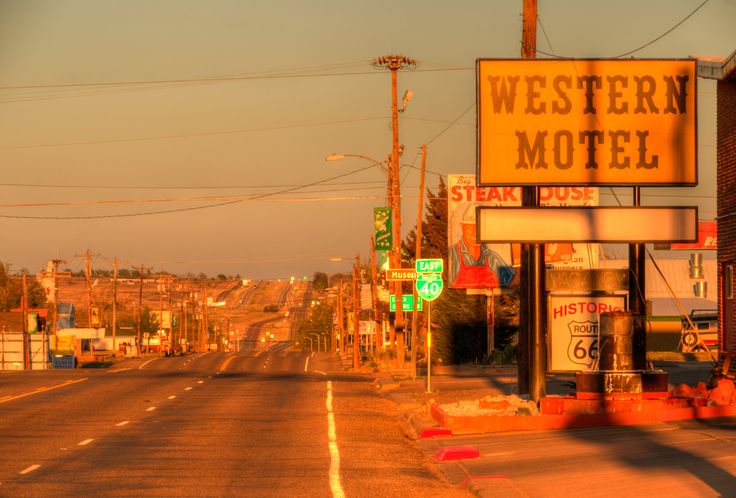 an old western motel sign on the side of a road