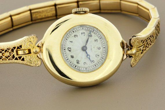 This wrist watch is by Agassiz Watch Co and the Wittnauer and Co. The case of the watch is down in 18K gold, is marked 2006, and the back of the case is engraved with a faint "AMB". The movement is Swiss, 18 jewel, and is marked 1365. The dial of the watch is engraved and enameled. The bracelet is 12K gold filled and is a stretch.The watch case measures 23.24mm wide, 26mm long, and sits 6.77mm tall.--Please reference our policy for more details--***For International orders, please provide a phon Antique Yellow Gold Watch Accessories With Subdials, Antique Yellow Gold Round Watches, Antique Yellow Gold Watch With Round Dial, Victorian Gold Watch With Chronometer, Victorian Style Gold Watch With Chronometer, Victorian Yellow Gold Watches For Anniversary, Victorian Yellow Gold Anniversary Watch, Victorian Yellow Gold Formal Watches, Antique Gold Watches With Subdials