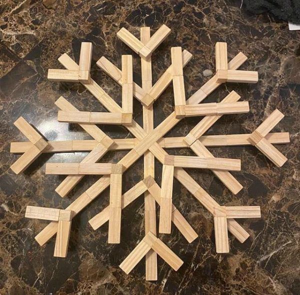 a snowflake made out of wooden sticks on a marble counter top with the word,