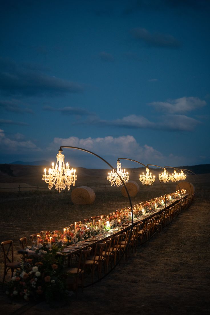 a long table is set up with candles and flowers in front of the chandelier