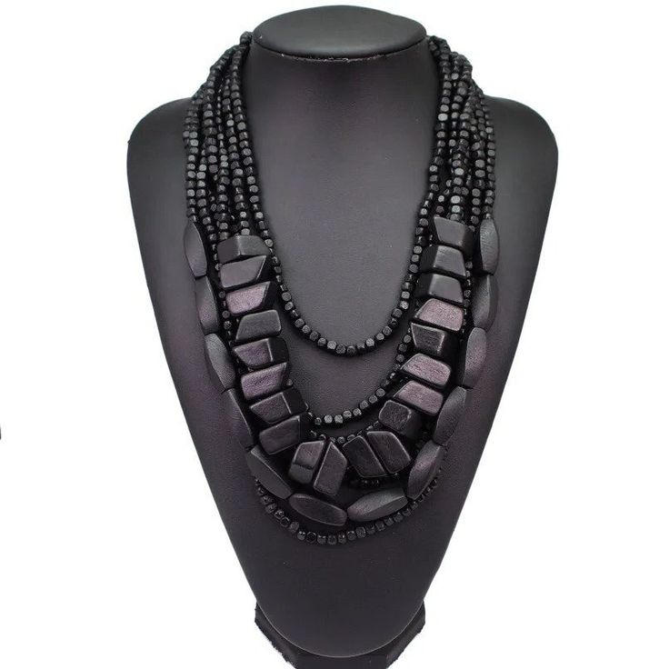 Discover the epitome of earthy elegance with our Bohemian Black Beaded Necklace, meticulously handcrafted to grace your ensemble with a touch of African tribal inspiration. This multi-strand statement piece boasts a harmonious blend of polished wooden elements and lustrous black beads, cascading in layers to create a bold aesthetic that's both timeless and contemporary. Perfectly suited for the fashion-forward individual, this necklace promises to be a versatile addition to your jewelry collecti Bohemian Multi-strand Black Bead Jewelry, Elegant Multi-strand Wooden Beads, Elegant Multi-strand Necklaces With Wooden Beads, Elegant Multi-strand Necklace With Wooden Beads, Bohemian Bib Necklaces For Jewelry Making With Black Beads, Black Bohemian Multi-strand Beads, Bohemian Black Multi-strand Beads, Black Bohemian Jewelry With Polished Beads, Bohemian Black Beaded Necklaces