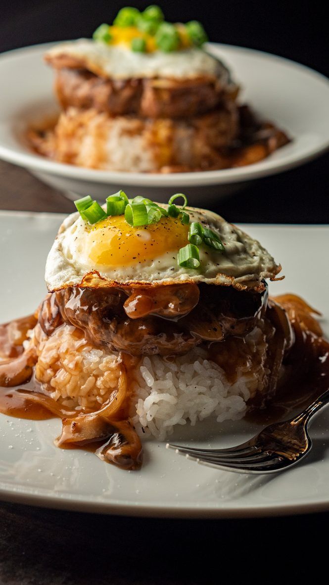 two white plates topped with rice and meat covered in gravy next to a fork