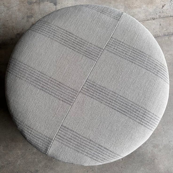 a round cushion sitting on top of a cement floor next to a white and gray wall