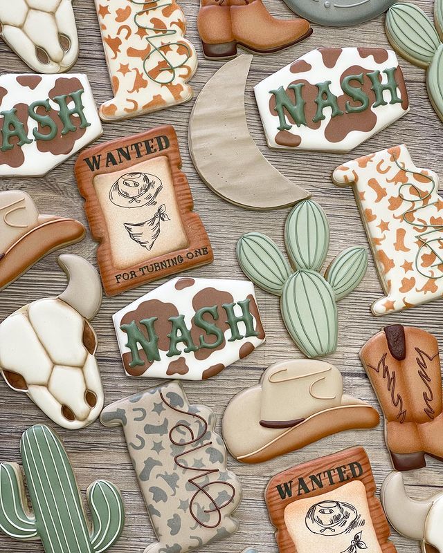 decorated cookies are arranged in the shape of hats, boots, and cactuses for western themed desserts