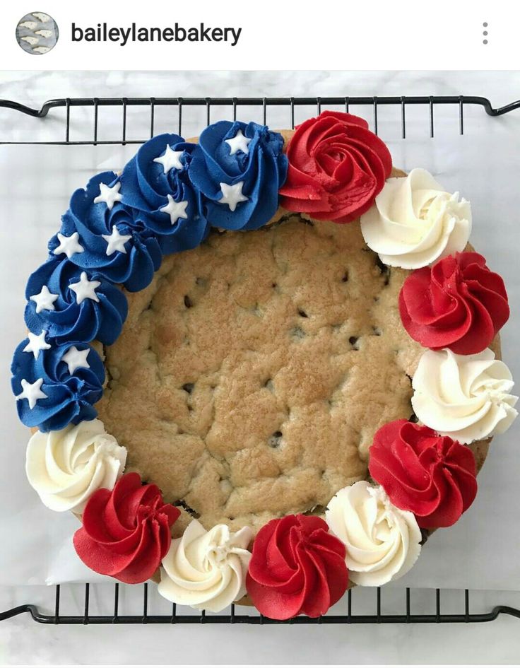 a cookie cake decorated with red, white and blue icing on a cooling rack