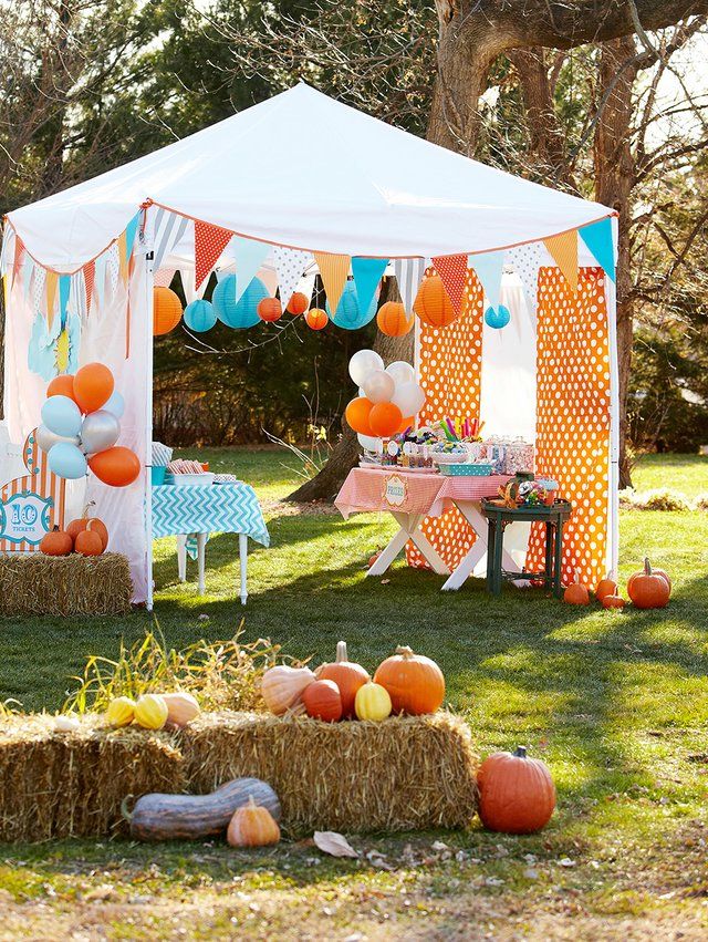 an outdoor party with hay bales and pumpkins on the grass under a tent