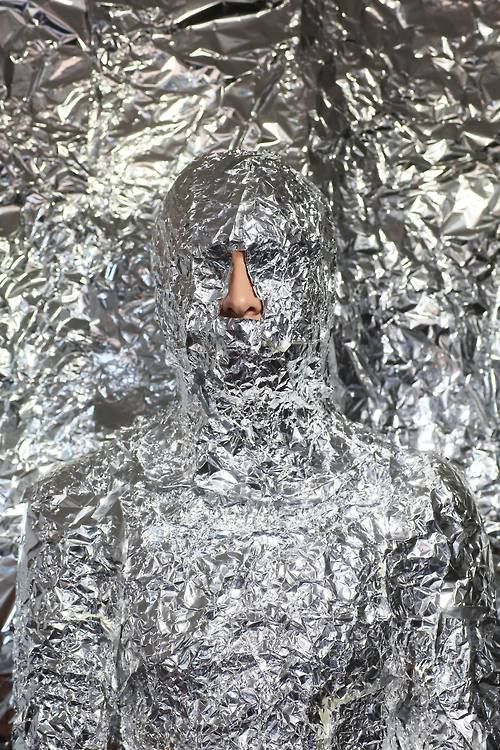 a man is covered in tin foil and has his face obscured by the plastic wrap