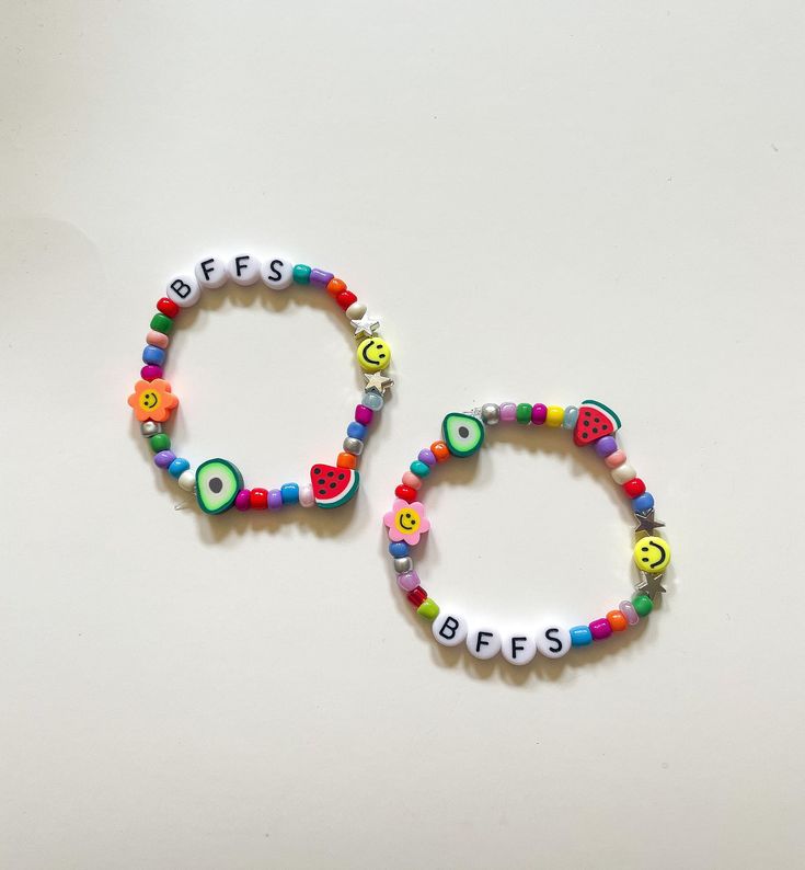 two bracelets with letters on them are sitting next to each other, one is made out of plastic beads