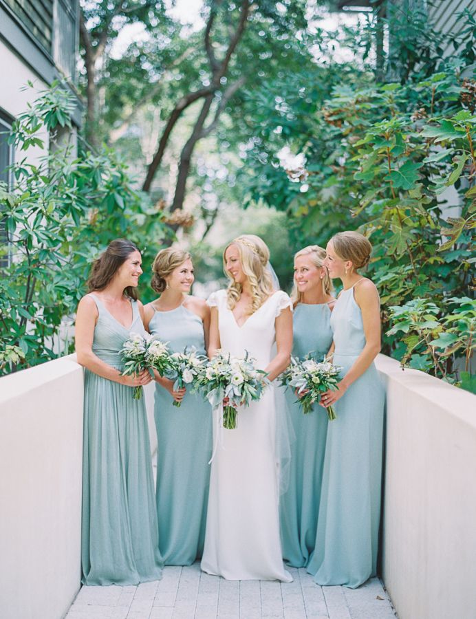 a group of women standing next to each other on top of a white wall holding bouquets