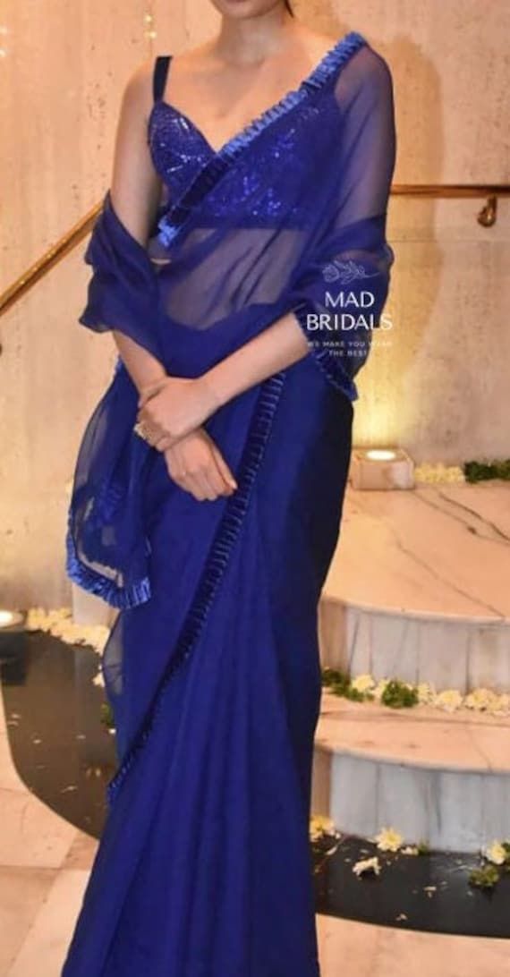 Elevate your style with our stunning Royal Blue Organza Silk Saree. It comes with a beautifully detailed border, and the blouse is hand-embellishments with sequins and stones for that extra touch of elegance. It comes with a stitched blouse according to your measurements This ensemble is perfect for making a statement at any event. Don't miss out on adding this touch of luxury to your wardrobe!  Unveiling the Details: Color: Royal Blue Craftsmanship: Masterful Handwork Fabric: Pure Organza  **Important Notes All our items are meticulously handmade and uniquely tailored for our valued customers. Expect minor variations in the actual product compared to the displayed image. Product color may slightly vary due to photographic lighting sources or your monitor settings. Please be advised that o Blue Tissue Silk Dupatta With Gota Work, Blue Pre-draped Saree With Unstitched Blouse In Tissue Silk, Blue Pre-draped Tissue Silk Saree With Unstitched Blouse, Tissue Silk Pre-draped Saree With Dupatta, Blue Bollywood Style Pre-draped Tissue Silk Saree, Blue Organza Pre-draped Saree With Pallu, Elegant Blue Pre-draped Saree With Dori Work, Organza Pre-draped Saree With Gota Work, Pre-draped Tissue Silk Saree With Gota Work