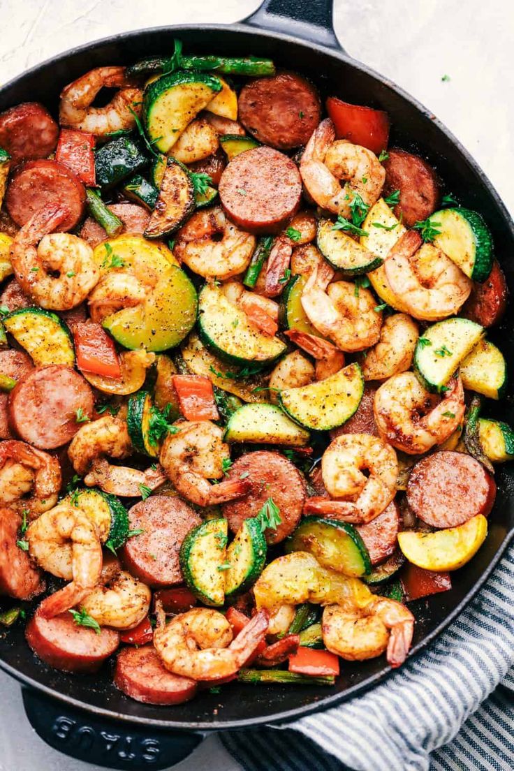 a skillet filled with shrimp, zucchini, and other veggies