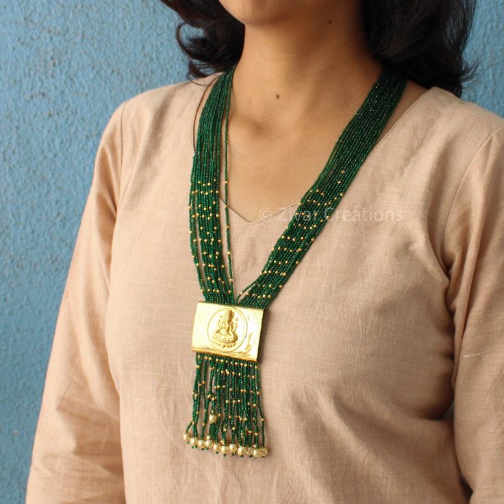 I made a Laxmi ji pendant using brass and added a layer of gold. I wanted to create a unique Indian handmade necklace. The necklace is decorated with small glass beads that are enhanced with gold plating, making it even more beautiful. It's 30 inches long and comes with an adjustable thread. The design is perfect for weddings, and the dangling pearls add an extra charm. Feel free to message me if you want any changes. I'm open to custom orders. Gold Pendant Necklace For Rituals, Gold Long Necklace As Festival Gift, Gold Long Necklace Gift For Festivals, Gold Long Necklace For Festivals And Gifts, Amulet Style Pendant Necklace With Beaded Chain, Amulet-style Pendant Necklace With Beaded Chain, Spiritual Brass Jewelry With Polished Beads, Handmade Traditional Necklace With Rectangular Pendant, Traditional Handmade Necklace With Rectangular Pendant