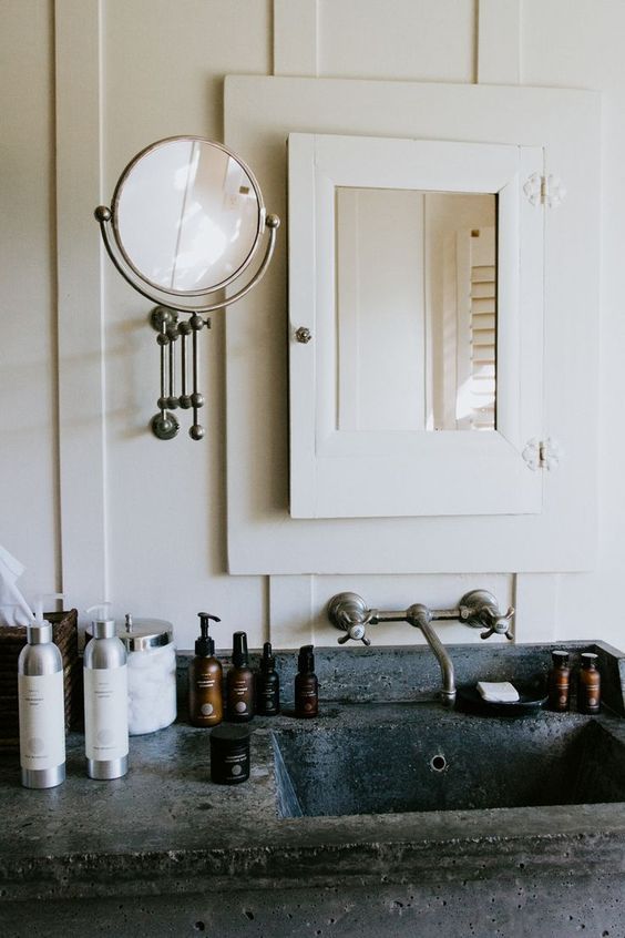 a bathroom sink sitting under a mirror next to a wall mounted faucet and soap dispenser