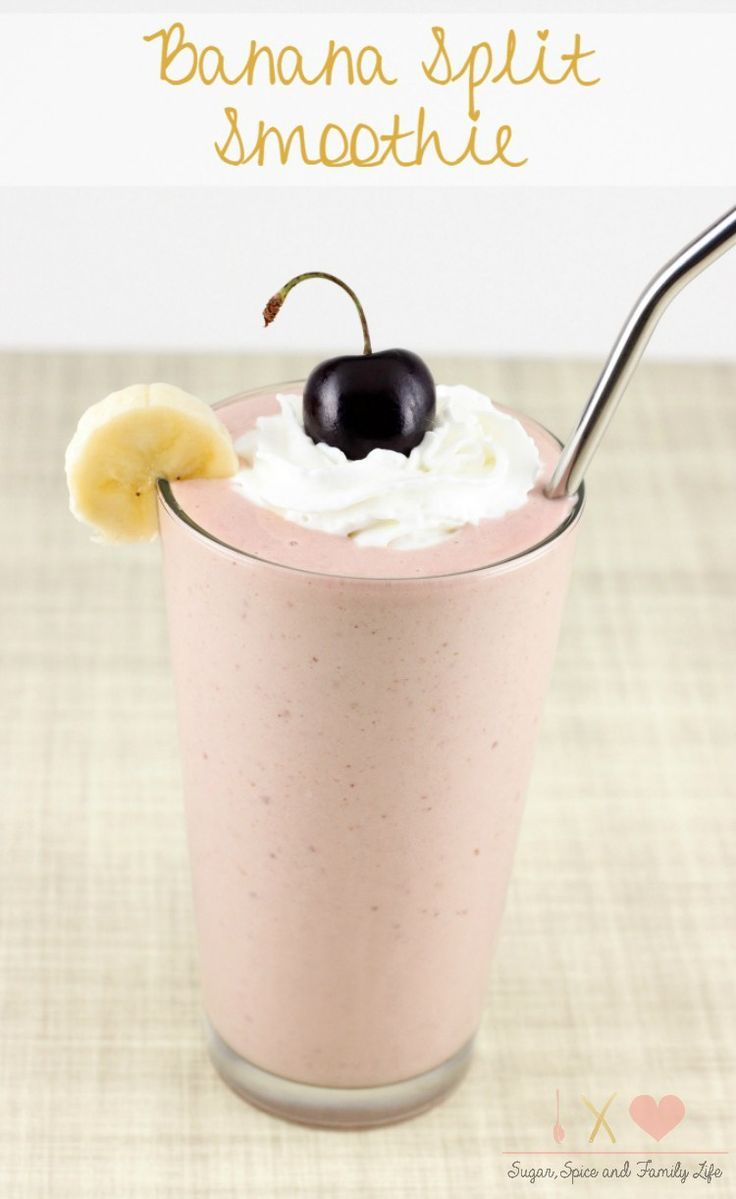 a banana split smoothie in a glass with whipped cream and a black cherry on top