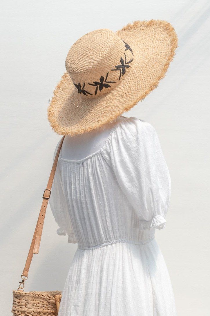 A classic summertime staple for a romantic warm-weather look, the Collioure Hat is perfect for days spent in the sunshine. With lovely vintage-inspired florals around the crown, this hat is available in tan straw with either black or white fleur details. Please Note- This item is final sale only. . Details: 17.5" Total Diameter 22" Around Crown, Adjustable Inner Ribbon Material: 100% Raffia, Polyester Inner Ribbon Imported Adjustable Summer Hats For Picnic, Elegant Straw Hat For Spring Picnic, Summer Curved Brim Boater Hat For Picnic, Summer Straw Boater Hat For Picnic, Summer Picnic Boater Hat With Curved Brim, Adjustable Panama Hat For Summer Picnic, Elegant Spring Hats For Picnic, Summer Curved Brim Panama Hat For Picnic, Wide Brim Sun Hat For Garden Party In Summer