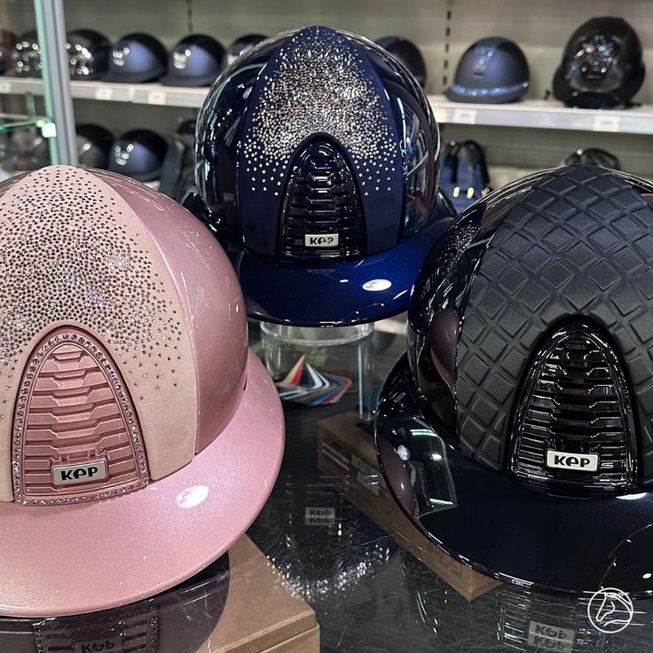 three different colored helmets are on display in a store window, one is blue and the other is pink