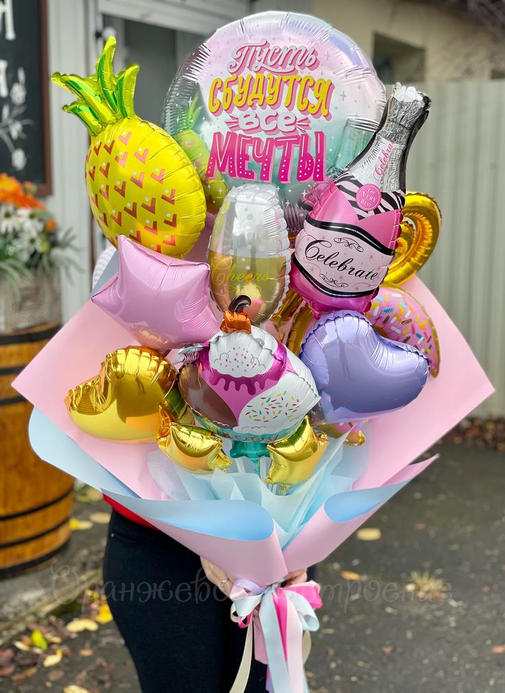 a woman holding a bunch of balloons and other items