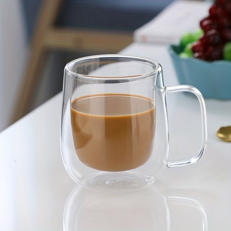 a glass mug with liquid in it sitting on a table