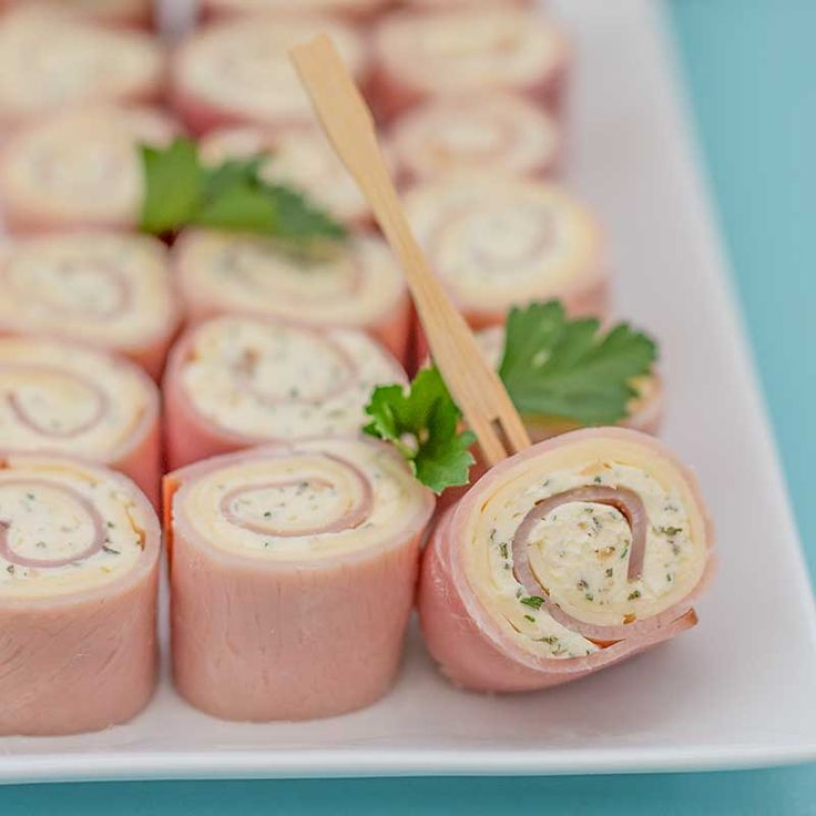 several rolls with meat and garnish are arranged on a plate