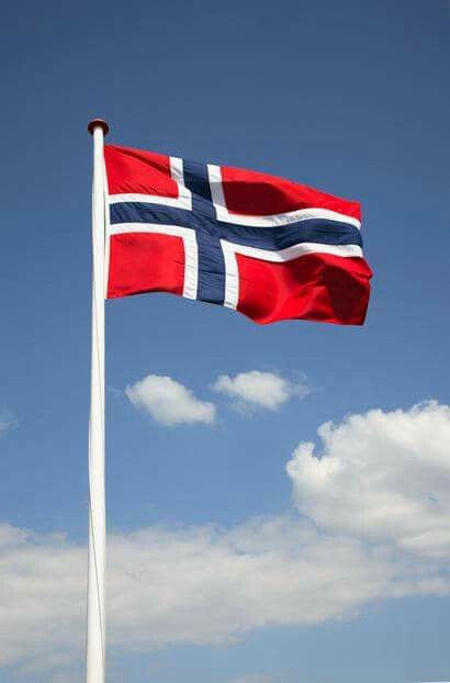 a flag flying in the wind on a clear day with blue sky and white clouds