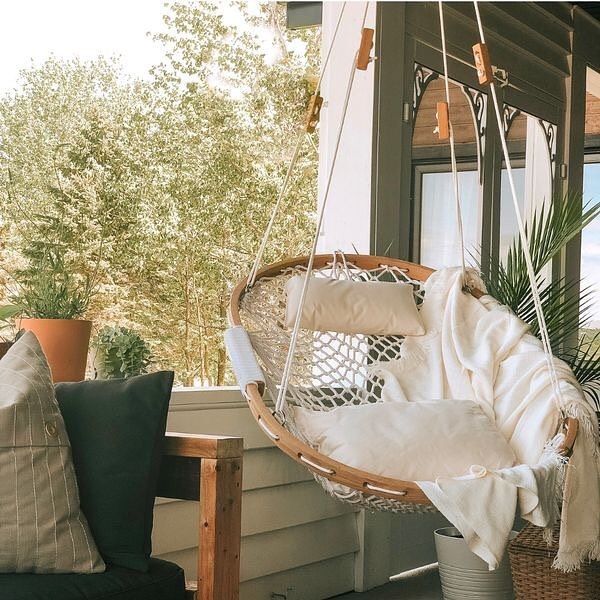 a hammock hanging from the side of a porch next to a potted plant