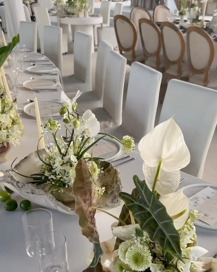 the table is set with white flowers and greenery for an elegant dinner or party