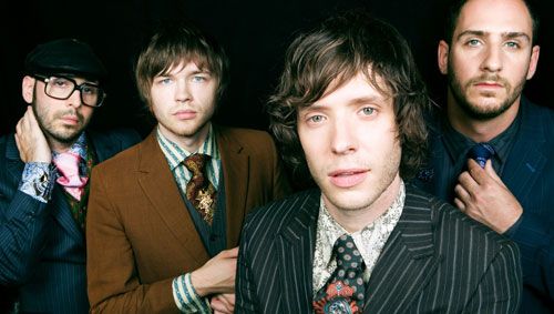 three men in suits and ties are posing for a photo with one man looking at the camera