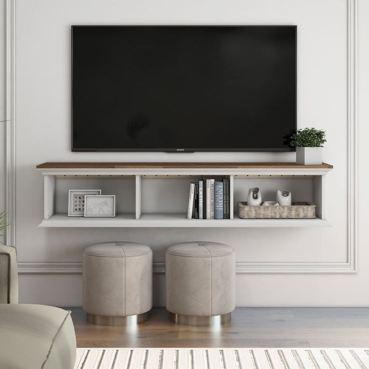 a flat screen tv mounted to the side of a white wall above two stools